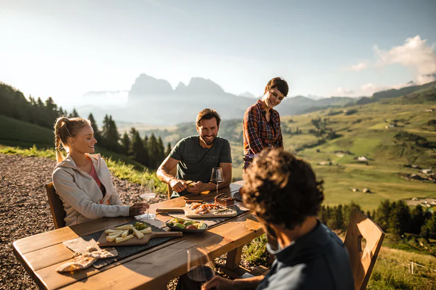 Vier Personen sitzen zusammen beim Essen mit einem Tal im Hintergrund