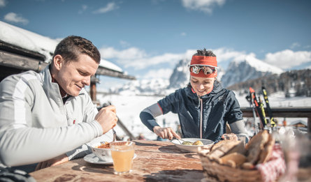Two people eating together in the mountains
