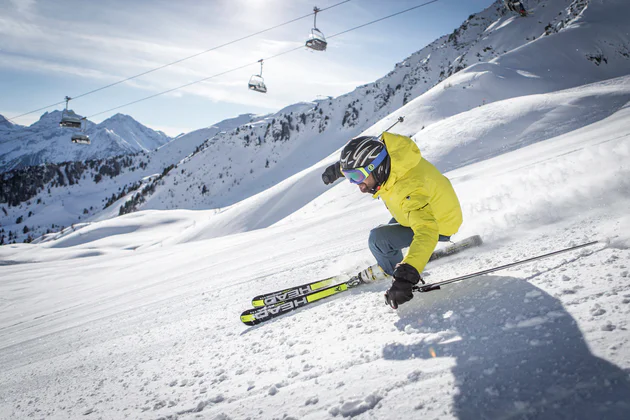 Skier in a neon yellow jacket descending the slope
