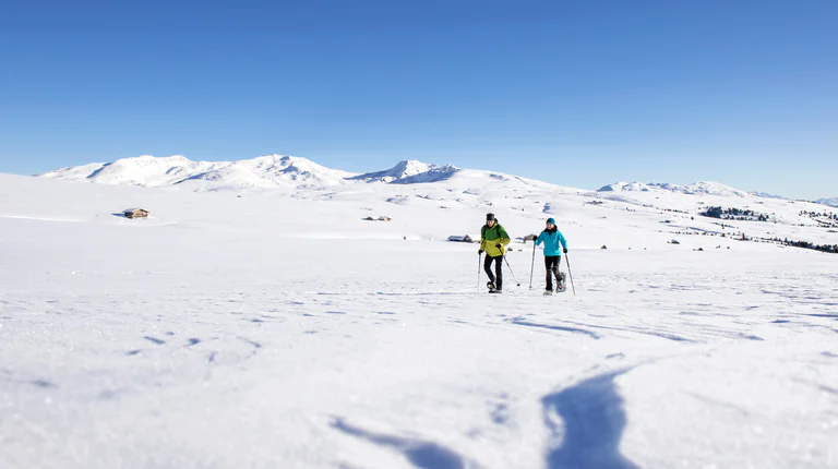 Due persone che camminano in un paesaggio invernale in montagna.
