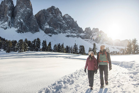 Two people hiking in winter with a mountain in the background 