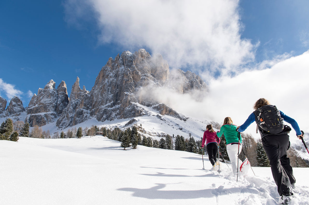 Drei Frauen auf Winterwanderung beim Bergaufstieg auf der Seiser Alm.