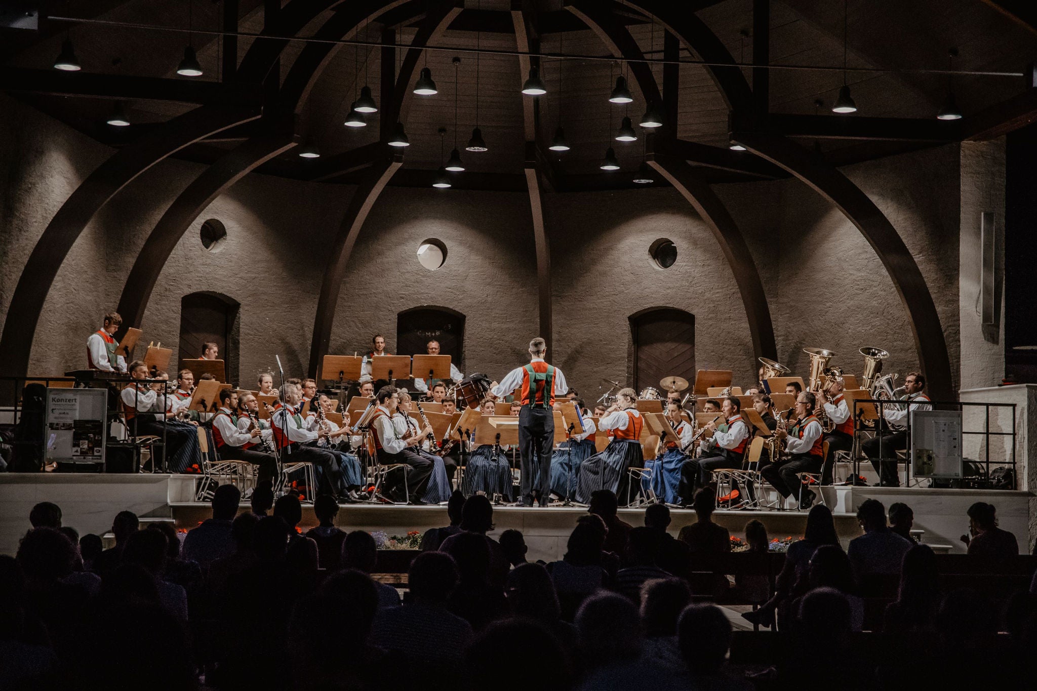 Eine Musikkapelle in traditioneller Tracht bei einem Konzert in einem Festsaal.