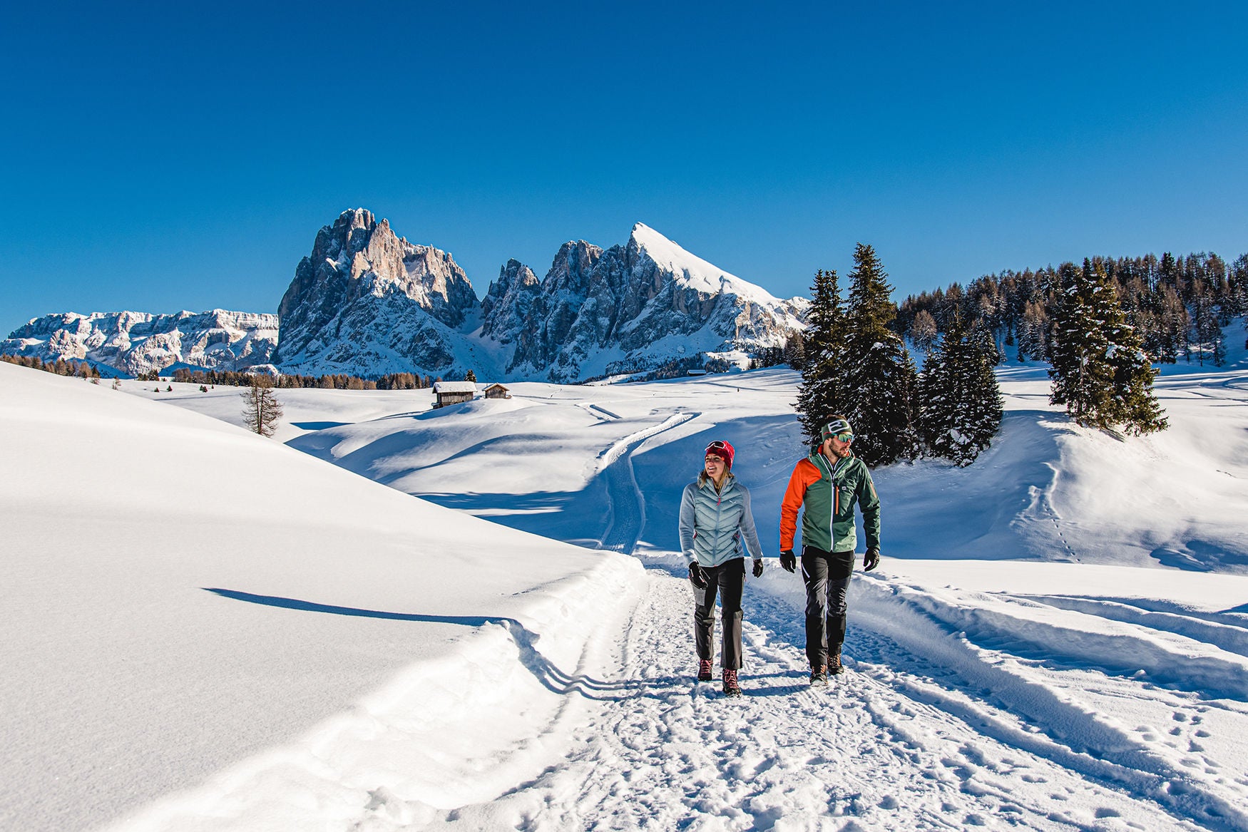 Paar beim Winterwandern auf dem Plateau der Seiser Alm mit Plattkofel und Langkofel im Hintergrund