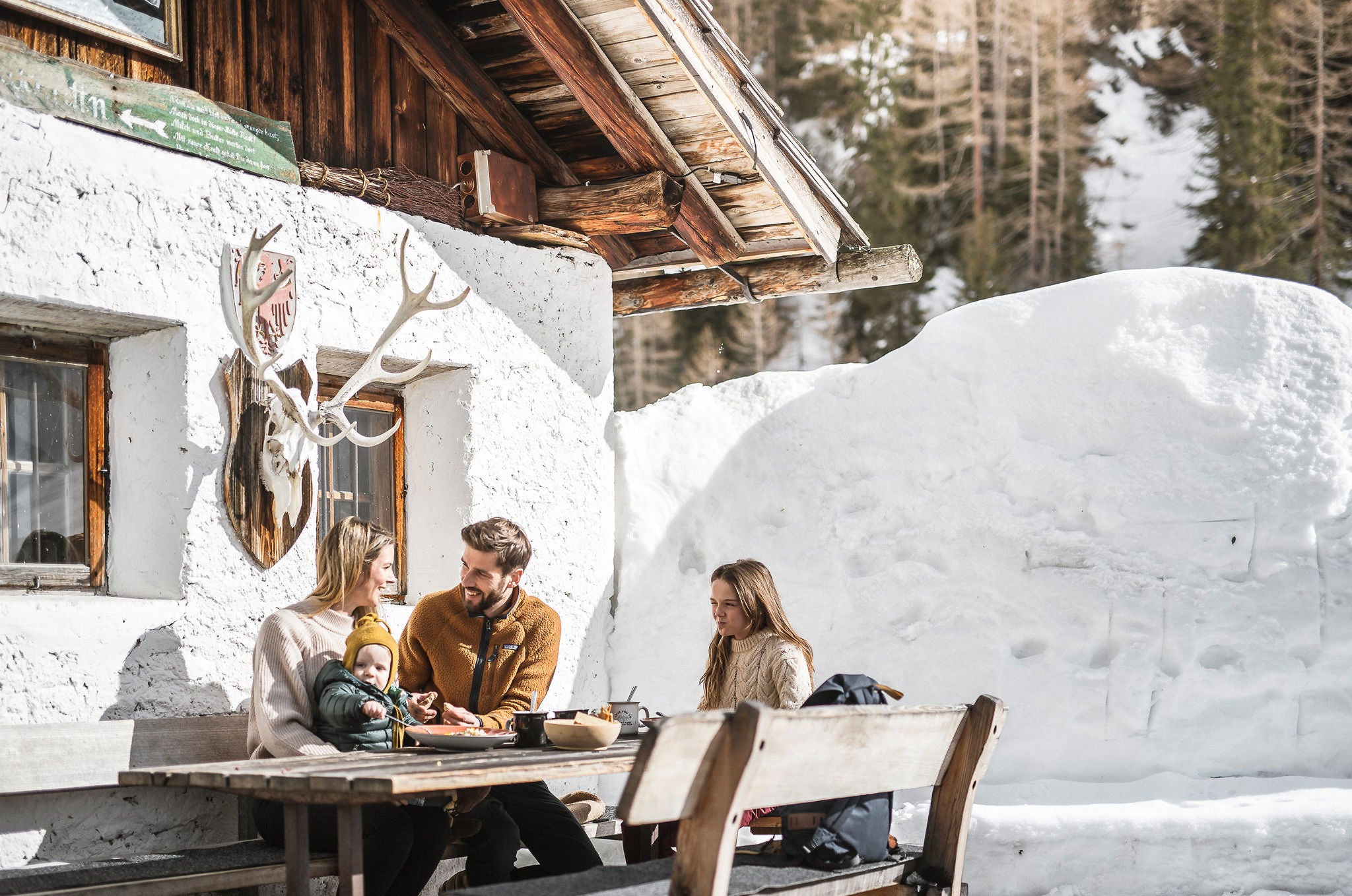 Eine Familie beim Mittagessen vor einer Almhütte im Ahrntal im Winter