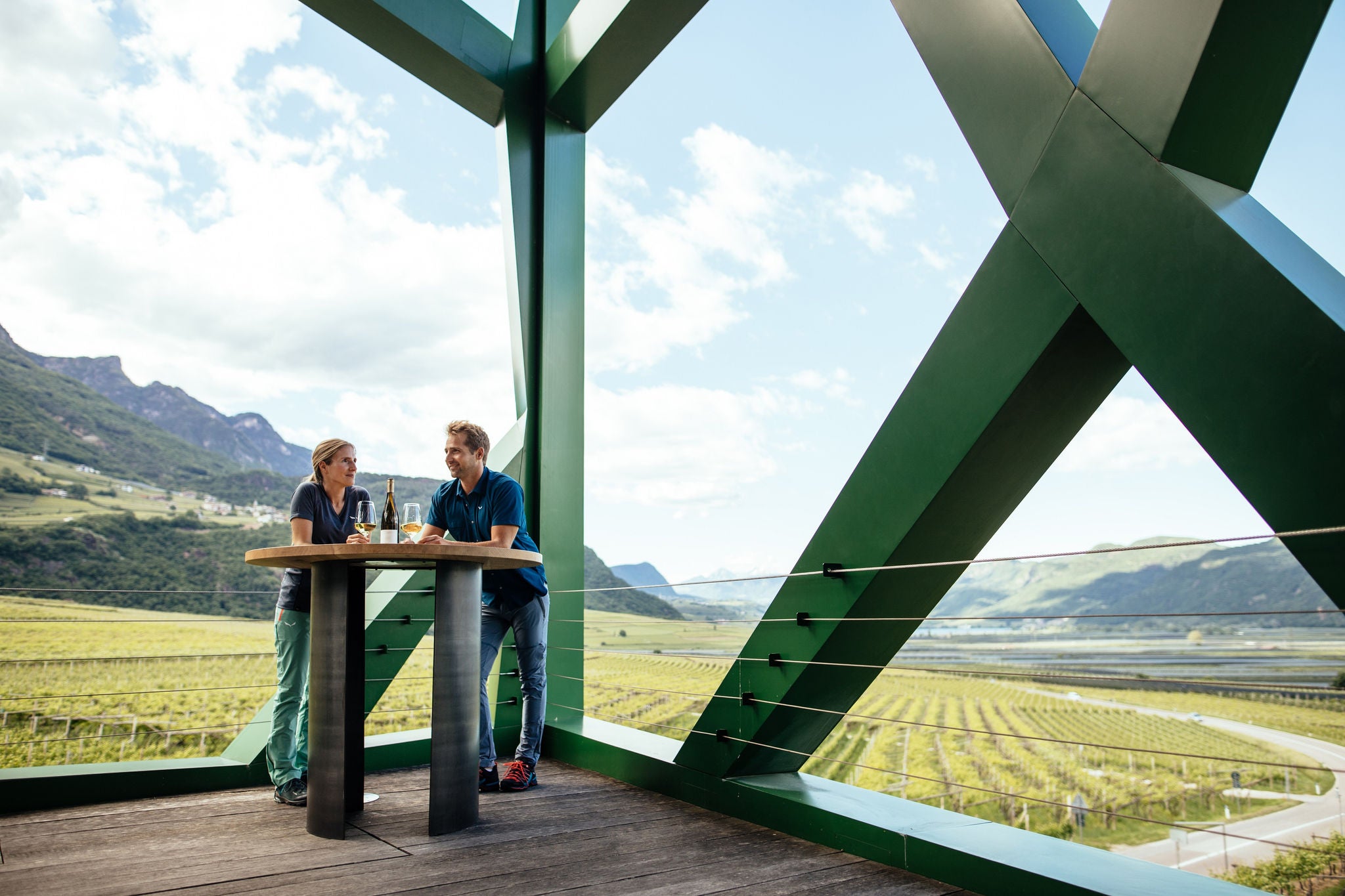 Eine Frau und ein Mann lehen an einem Verkostungstisch auf der Terrasse der Kellerei Tramin.