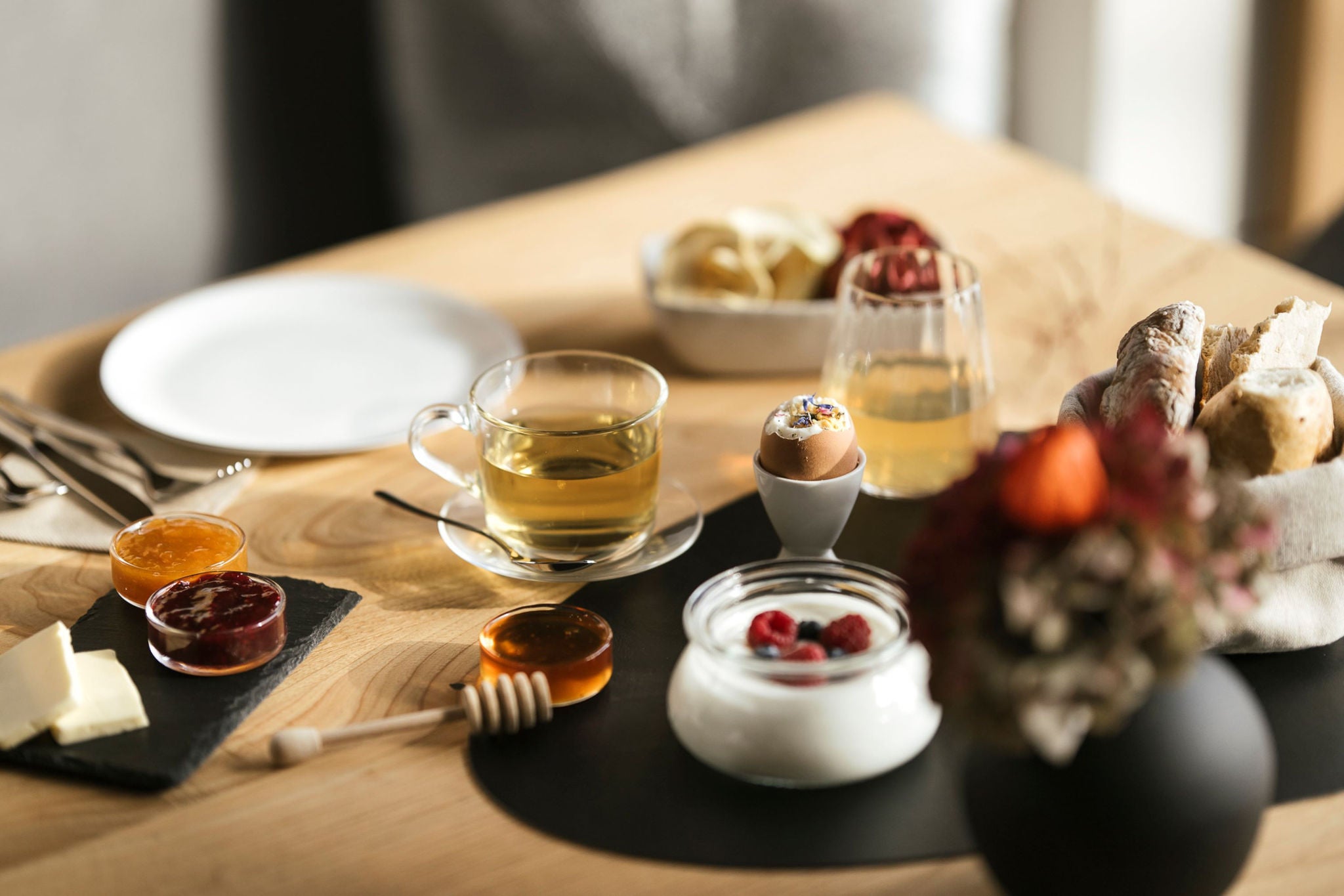 Honig, Eier, Tee, Brot und Joghurt aus Südtirol auf dem Frühstückstisch.