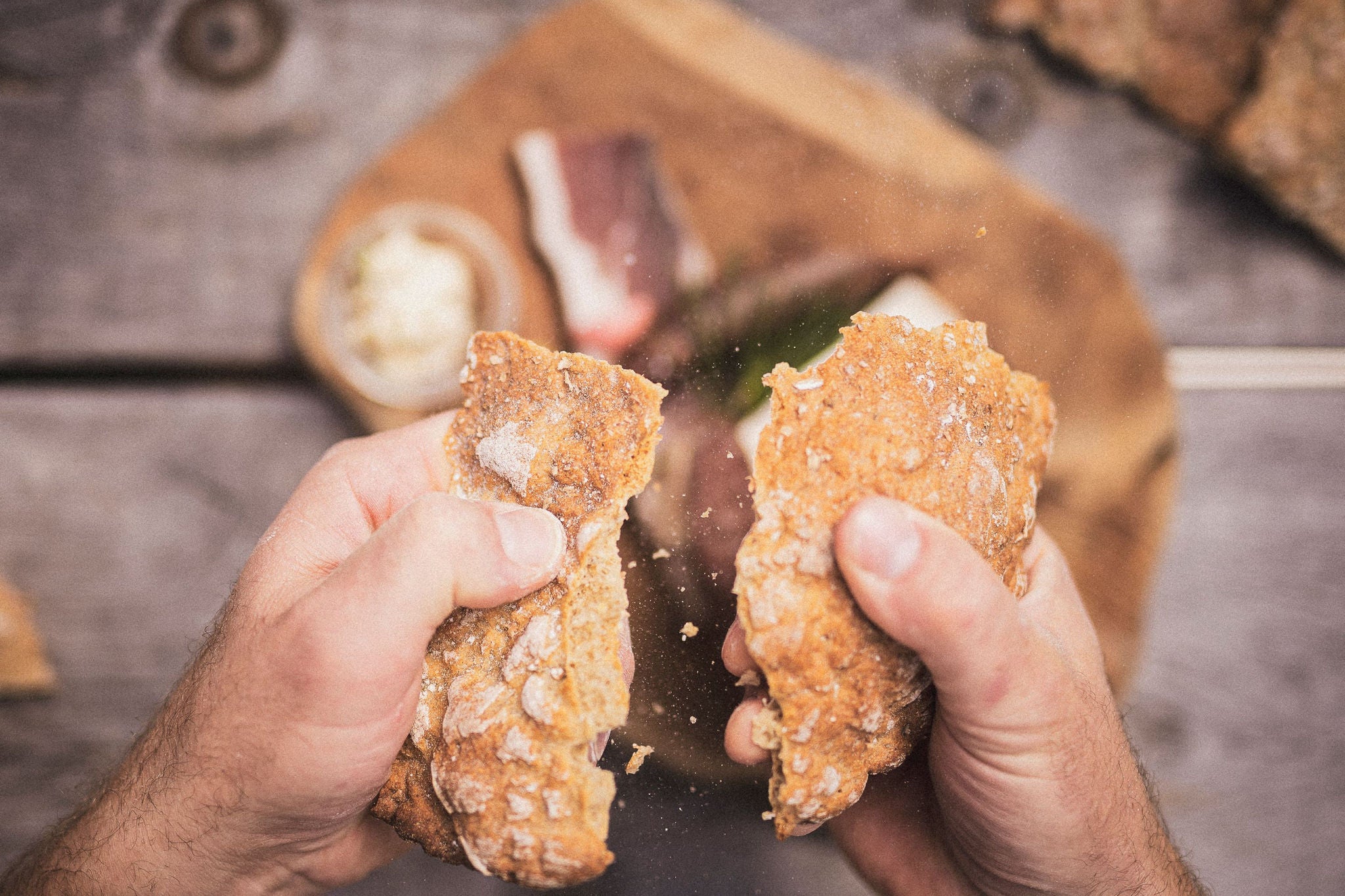 Zwei Männerhände zerbrechen ein Stück Schüttelbrot, das zu einer Brotzeit  gereicht wurde.