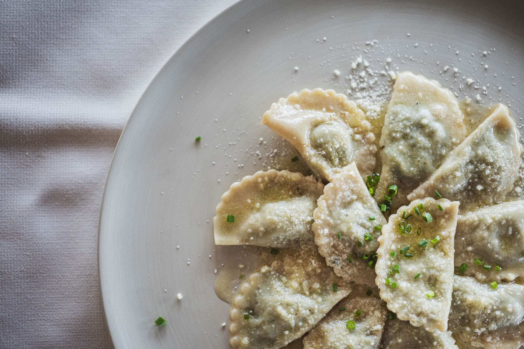 Ein Teller mit Schlutzkrapfen mit Parmesan und Schnittlauch garniert.