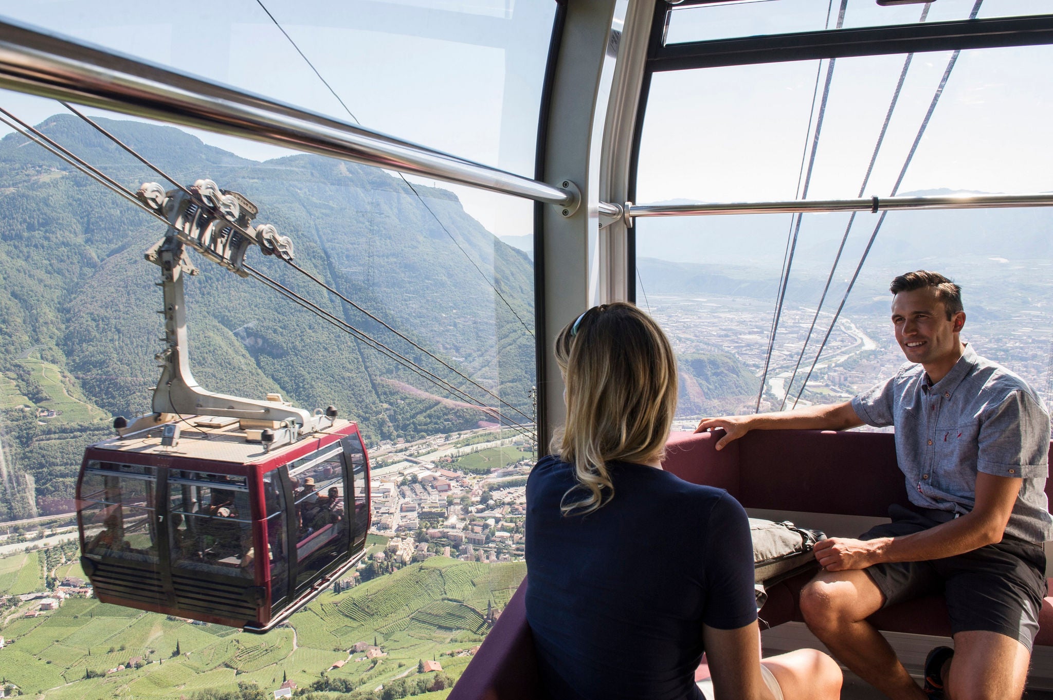 Eine Frau und ein Mann sitzen in der Rittner Seilbahn mit Blick auf Bozen