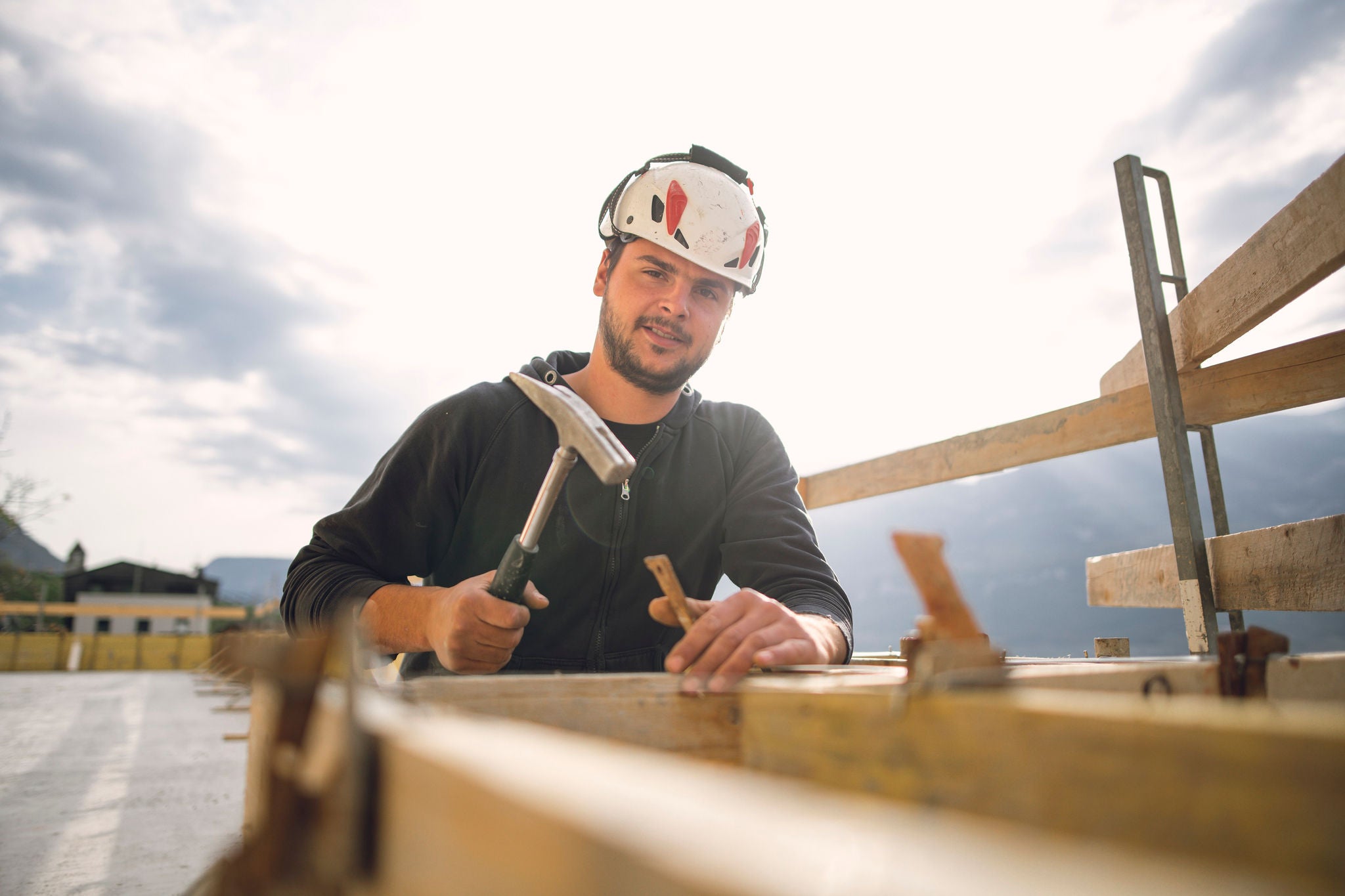 Ein Handwerker bearbeitet Holz auf einem Dach