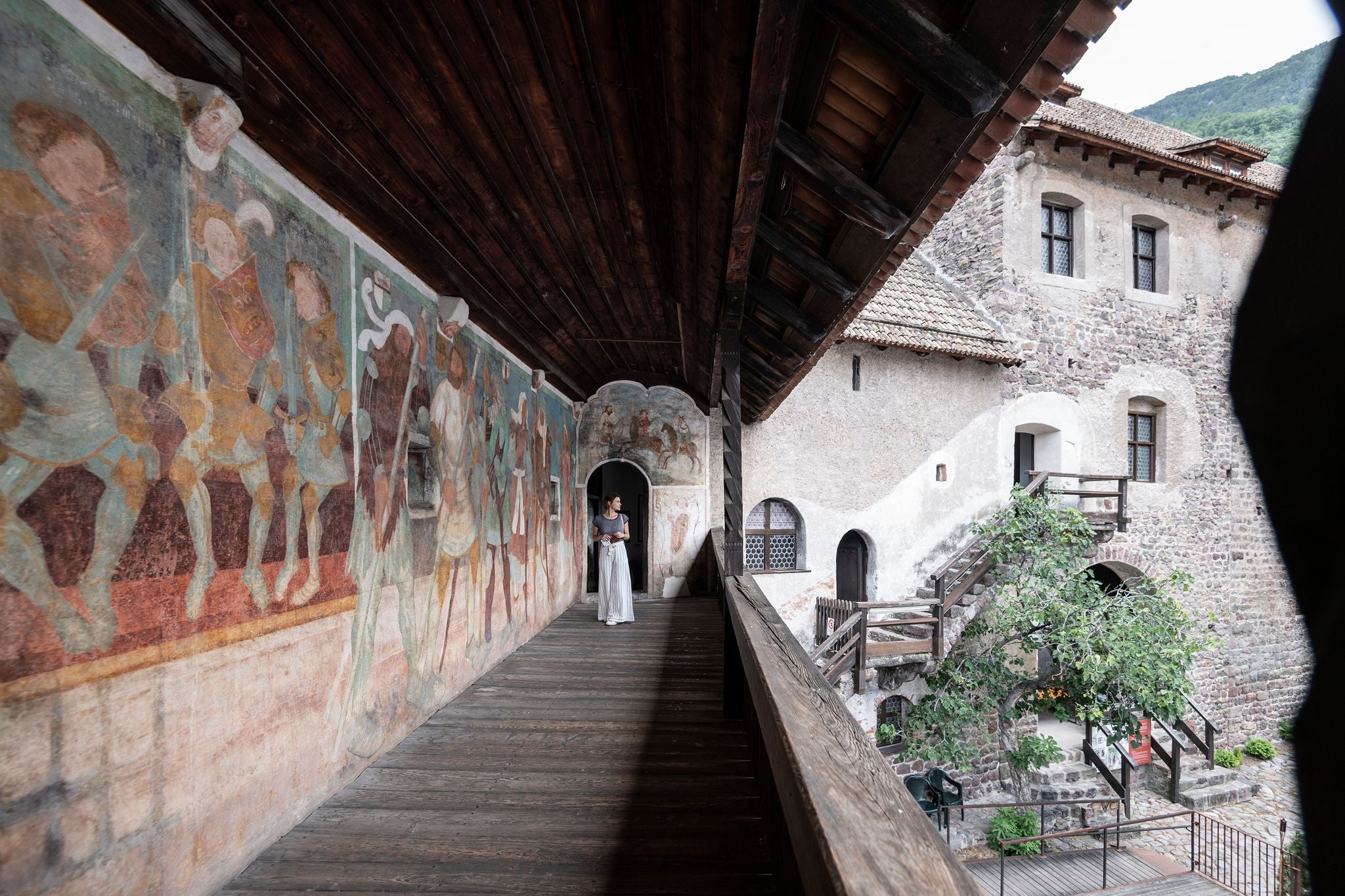 Eine Person läuft über einen Balkon im Schloss Runkelstein bei guten Wetter