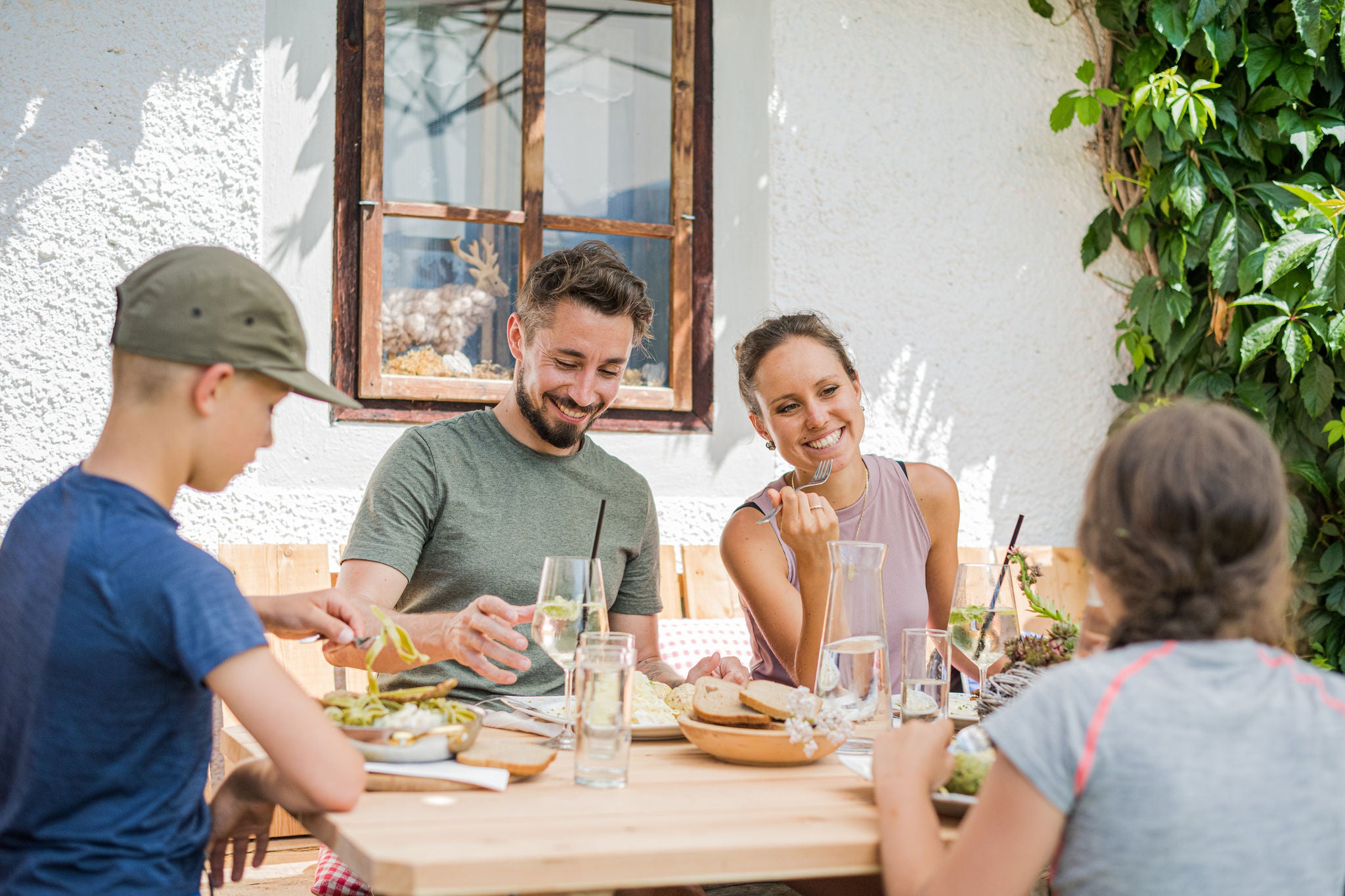 Familie mit zwei Kindern beim Mittagessen vor einem Gashof im Ahrntal