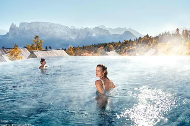 Zwei Frauen entspannen im Pool mit Blick auf die Dolomiten