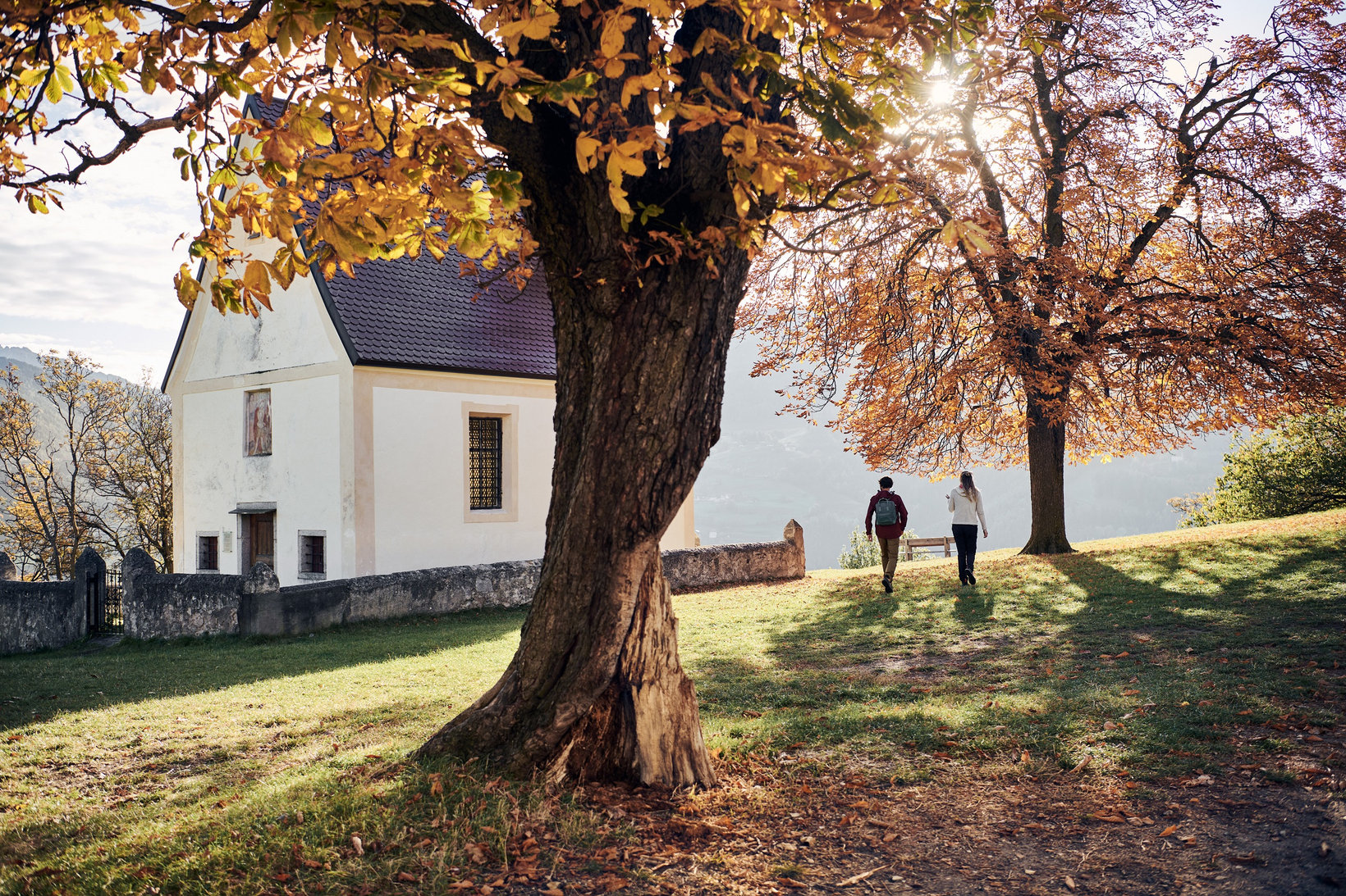 Una coppia fa una passeggiata autunnale accanto ad una chiesetta