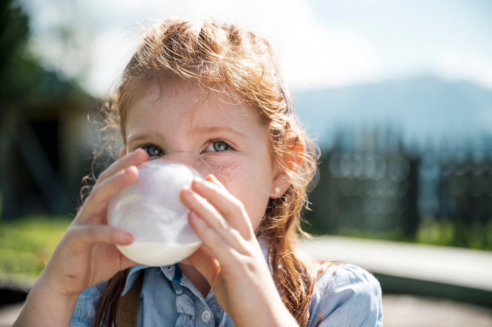 Child drinking a glass of milk outdoors