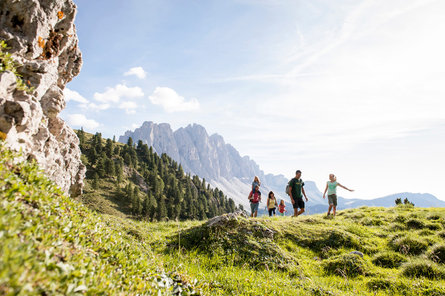 Una famiglia in escursione con una catena montuosa sullo sfondo nella regione della Valle di Villnöss, nelle Dolomiti