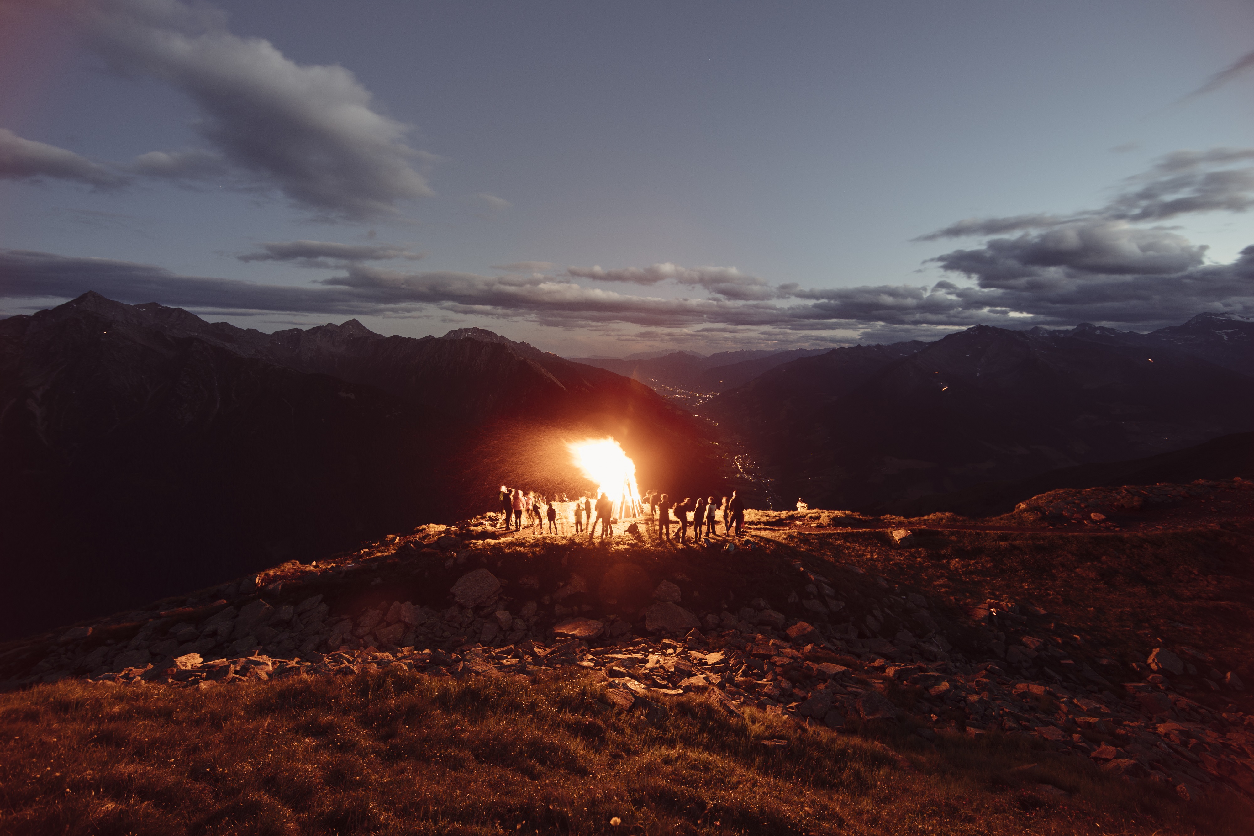 Im Passeiertal mit Blick in Richtung Meran haben sich Einheimische an einem Juni-Abend um ein traditionelles Herz-Jesu-Feuer versammelt.