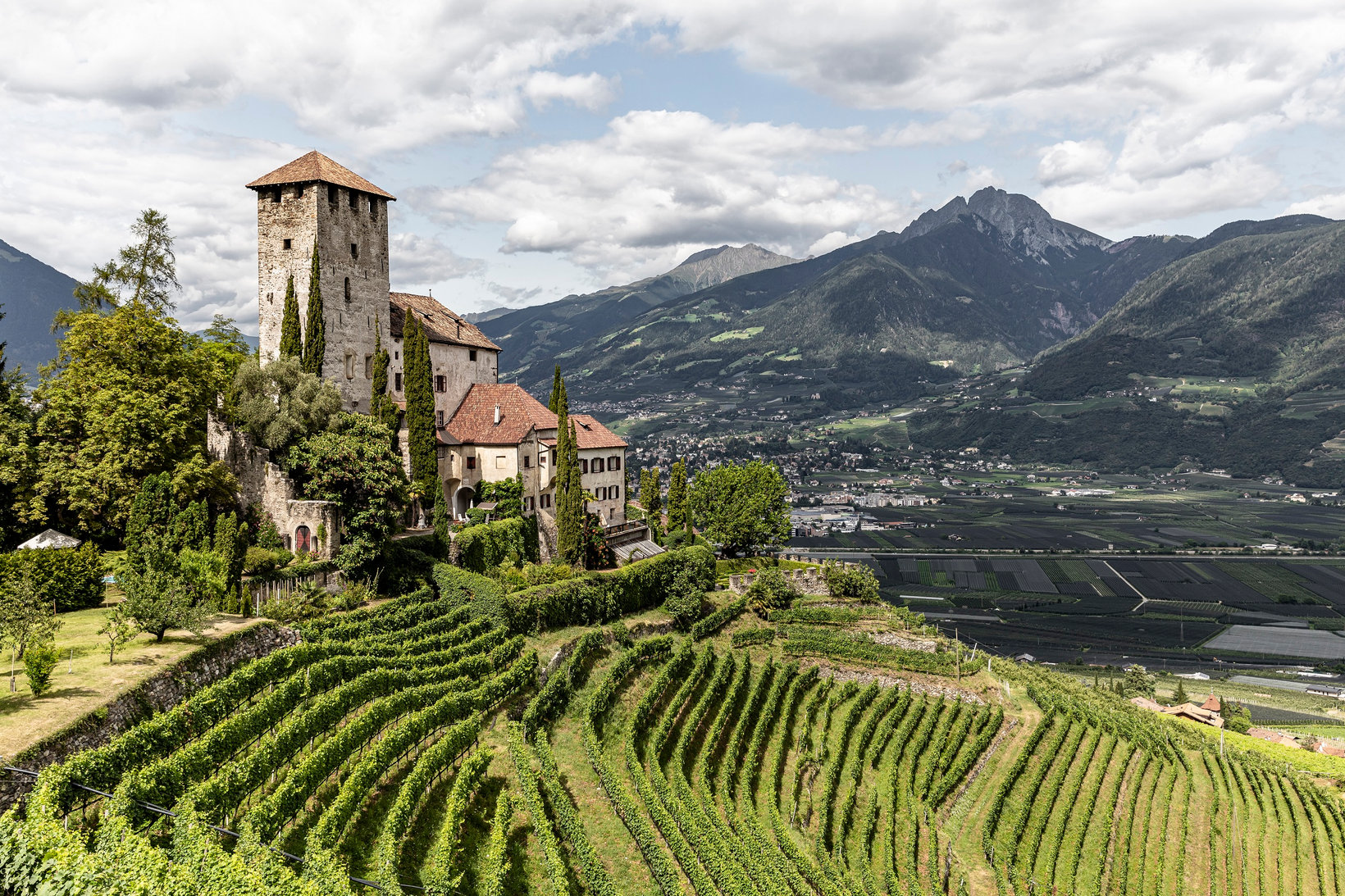 W letni dzień idylliczny zamek Lebenberg w pobliżu Marling wznosi się nad winnicami rozciągającymi się na zboczu doliny. 